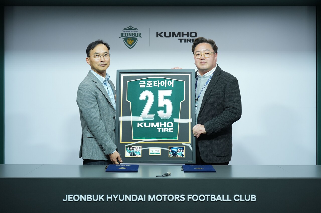 (왼쪽부터) 윤민석 금호타이어 G.마케팅담당 상무와 이도현 전북현대모터스 단장이 공식 파트너십 연장조인식을 체결하며 금호타이어 로고가 적용된 유니폼 액자를 들고 기념사진을 찍고 있다. (출처=금호타이어)