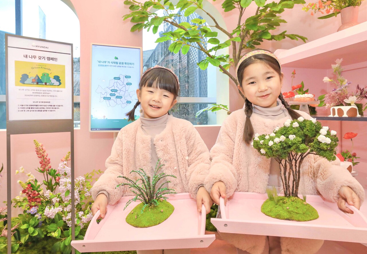 26일 오전, 서울시 양천구 현대백화점 목동점 7층 보타닉 하우스에 마련된 ‘서울마이트리-내 나무 갖기’ 팝업스토어에서 캠페인에 참여한 아이들이 식재할 나무 모형을 들고 포즈를 취하고 있다. (출처=현대백화점)