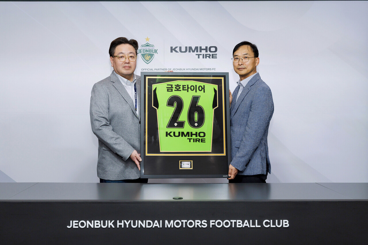 (오른쪽) 윤민석 금호타이어 G.마케팅담당 상무와 이도현 전북현대모터스 단장이 공식 파트너십 연장 조인식을 체결하며 금호타이어 로고가 적용된 유니폼 액자를 들고 기념사진을 찍고 있다. (출처=금호타이어)